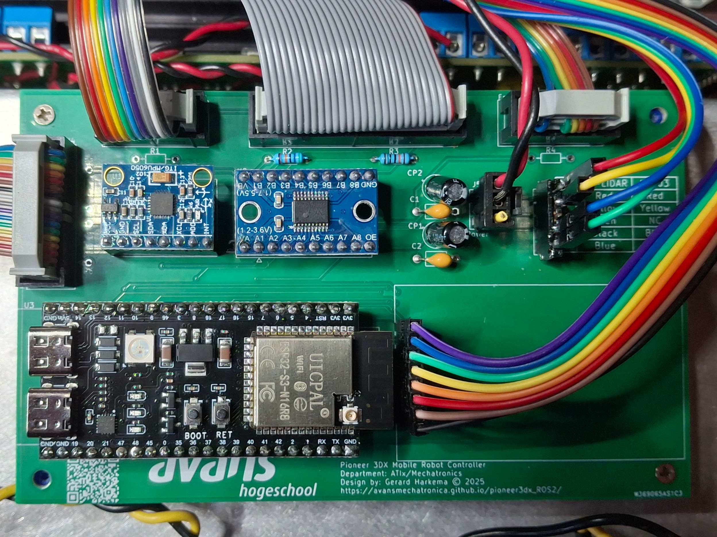 Green PCB circuit board labeled avans hogeschool showing Pioneer 3DX Mobile Robot Controller with ESP32-S3-WROOM microcontroller module, multiple rainbow-colored ribbon cables, blue sensor modules, capacitors, and various electronic components. Board designed by Gerard Harkema for Alix/Mechatronics Department in 2025